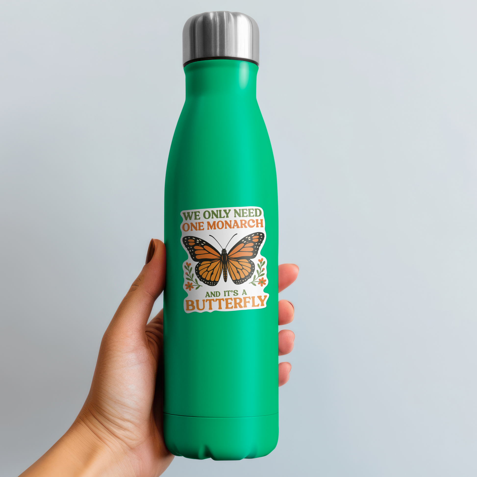 Green water bottle with butterfly design held by a hand against a light gray background